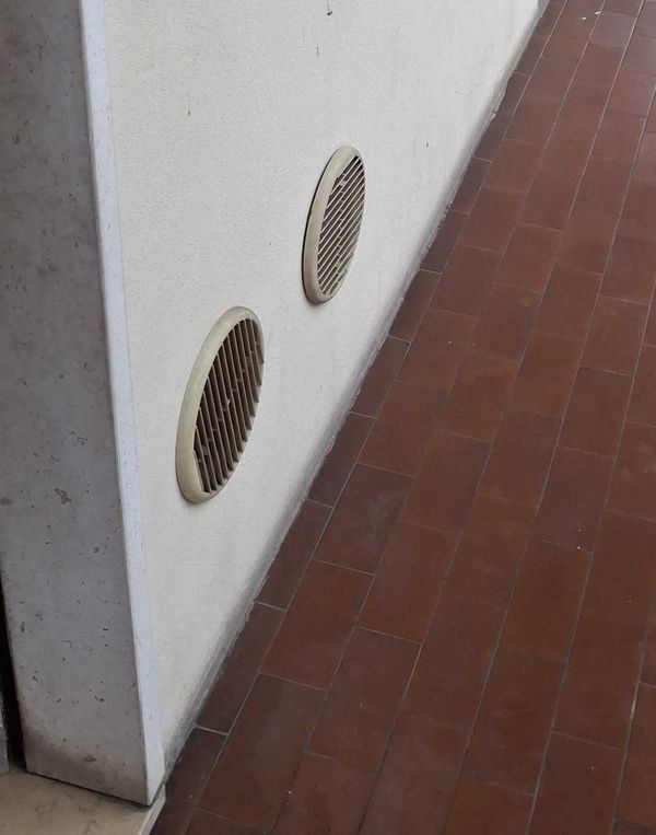 Griglie di ventilazione circolari nella parete esterna della cucina a livello del pavimento