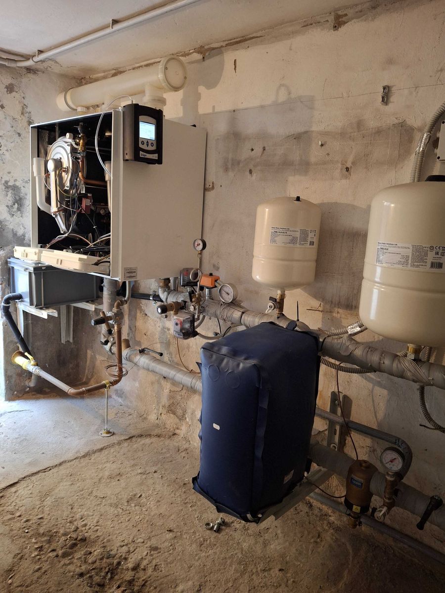 Seconda centrale termica condominiale: caldaia a condensazione a due moduli con il pannello frontale aperto, vasi di espansione e collettori