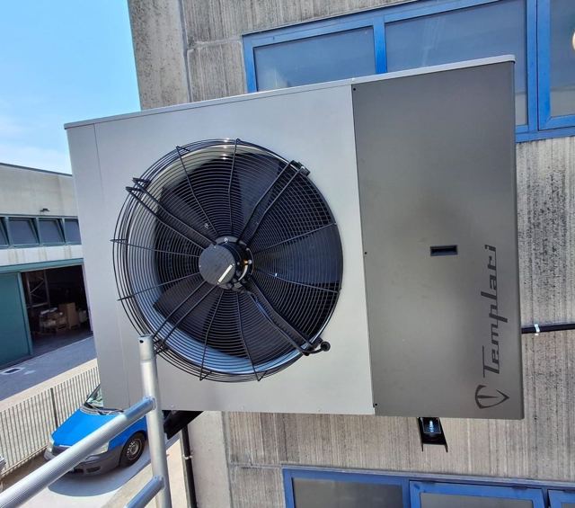 Unità esterna di una pompa di calore aria-aria fissata alla parete del capannone SAEM a Martellago, installata da ErgonSì