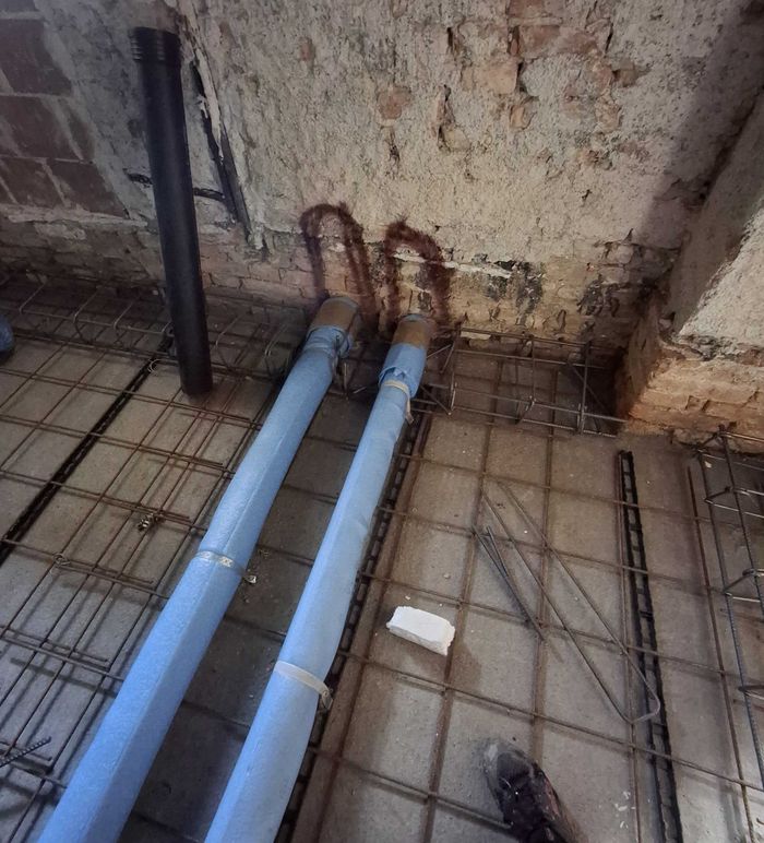 Due tubazioni di scarico che entrano nel muro portante, sigillate con schiuma