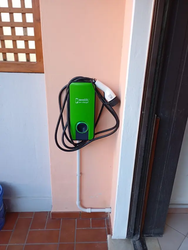 Wallbox verde per la ricarica domestica di un’auto elettrica installata a parete
