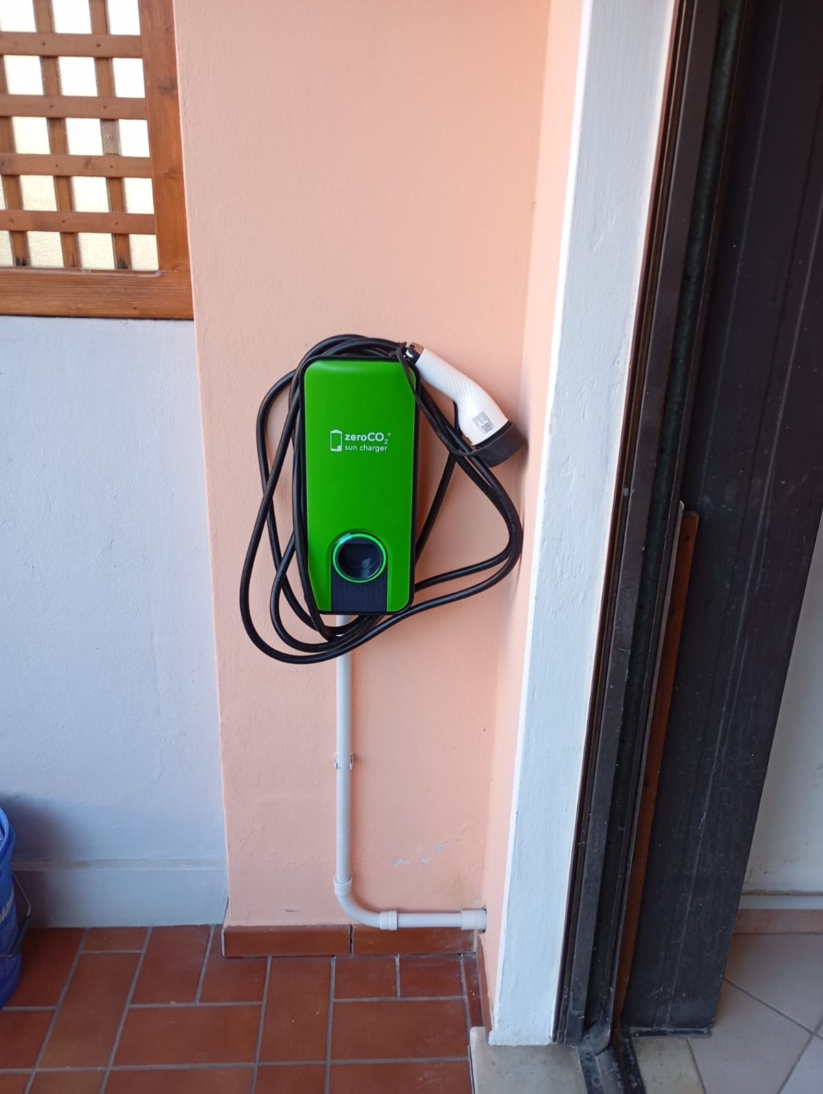 Wallbox verde per la ricarica domestica di un’auto elettrica installata a parete